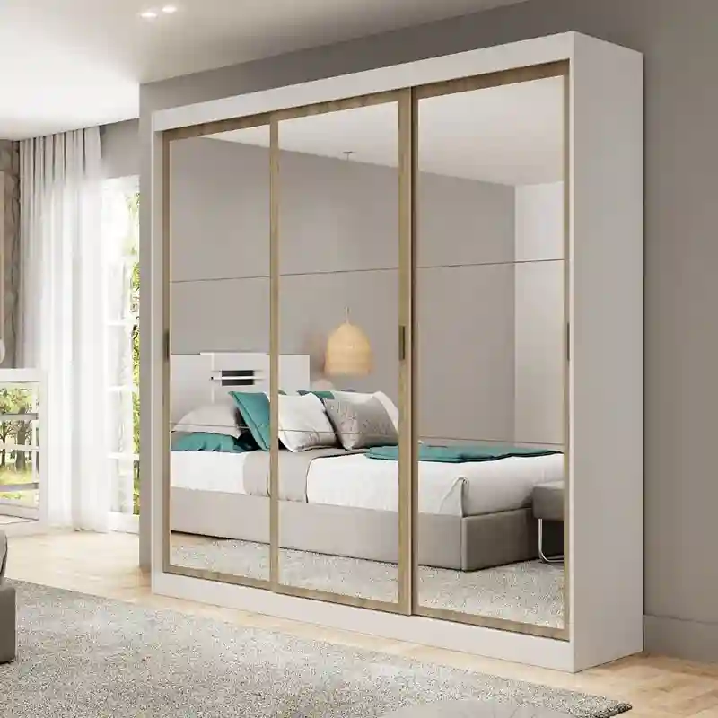 Guarda-roupa grande de casal com estrutura externa branca e três portas de correr totalmente espelhadas com molduras de madeira clara. Os espelhos das portas refletem uma cama de casal arrumada com travesseiros brancos e azuis em um quarto aconchegante e bem iluminado.